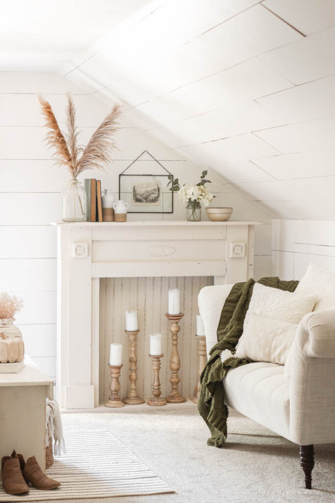 vintage mantle with wood candlesticks and candles in the faux firebox next to a settee