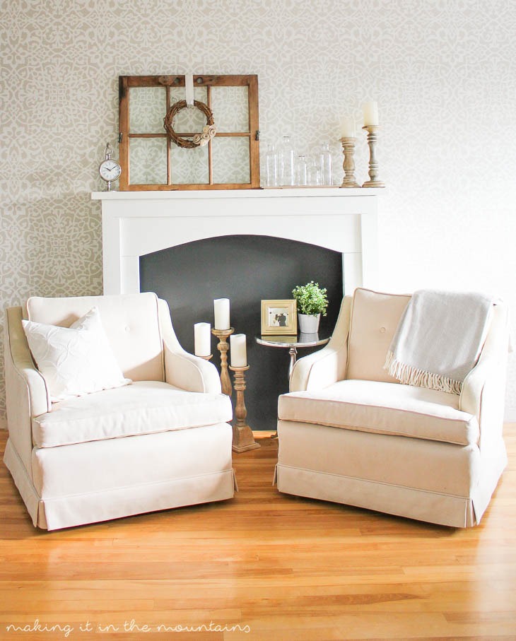 fake fireplace with inside painted black and two armchairs sitting in front of it