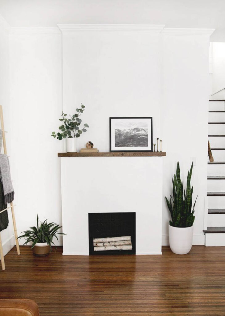 faux white fireplace with wood mantle and fake log insert