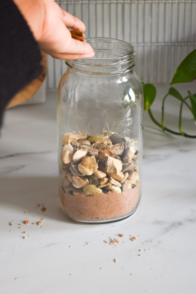 mason jar has sand added to it and next some pebbles/small rocks