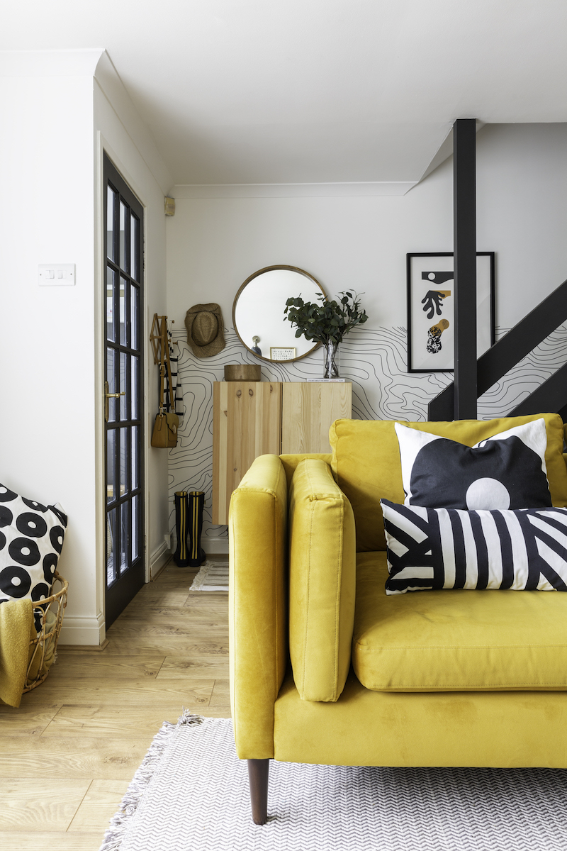 Yellow sofa in living room with Ikea Ivar cabinet on the wall in the entryway behind it.